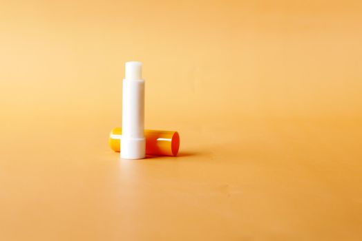 moisturising lip balm on orange background .