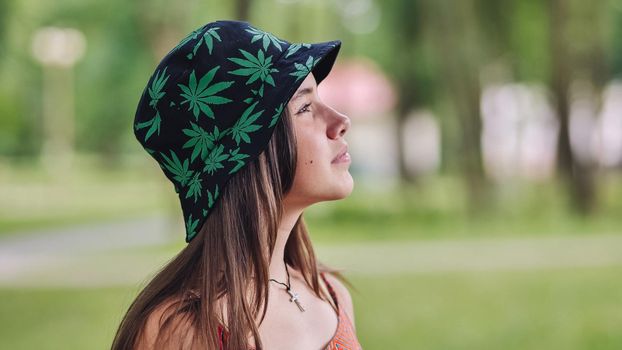 Profile view of a beautiful teenage girl in a park on a summer day in a panama hat