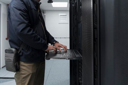 Close up on Data Center Engineer hands Using keyboard on a supercomputer. Server Room Specialist Facility with Male System Administrator Working with Data Protection Network for Cyber Security.