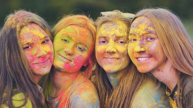 Cheerful girls posing smeared in multi-colored powder