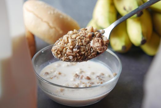 putting musli in a bowl full of milk on table .