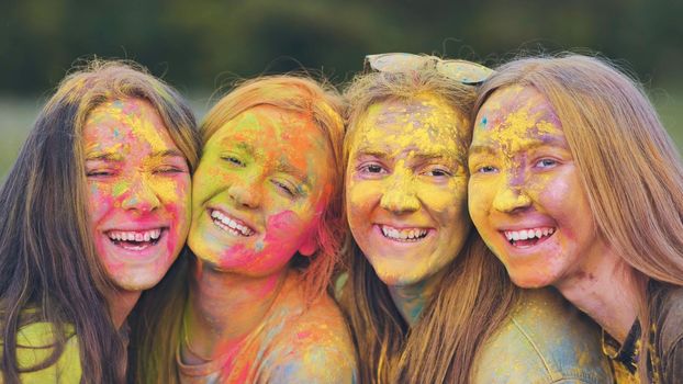 Cheerful girls posing smeared in multi-colored powder