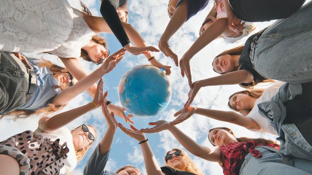 Earth conservation concept. 11 girls surround the rotating earth globe with their palms hands