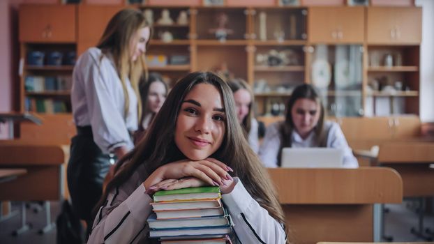 A student poses with textbooks at her desk in her class