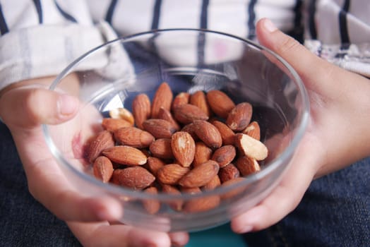 child holding a bowl of almond .