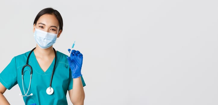 Covid-19, coronavirus disease, healthcare workers concept. Smiling cheerful asian doctor, nurse in medical mask and rubber gloves prepare syringe with vaccine for shot vaccination, white background.