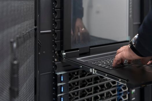 Close up on Data Center Engineer hands Using keyboard on a supercomputer. Server Room Specialist Facility with Male System Administrator Working with Data Protection Network for Cyber Security.