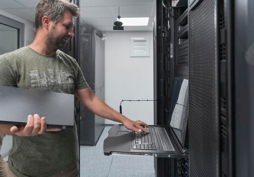 Close up on Data Center Engineer hands Using keyboard on a supercomputer. Server Room Specialist Facility with Male System Administrator Working with Data Protection Network for Cyber Security.