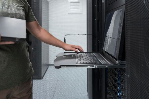 Close up on Data Center Engineer hands Using keyboard on a supercomputer. Server Room Specialist Facility with Male System Administrator Working with Data Protection Network for Cyber Security.