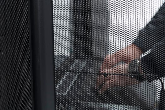 Close up on Data Center Engineer hands Using keyboard on a supercomputer. Server Room Specialist Facility with Male System Administrator Working with Data Protection Network for Cyber Security.