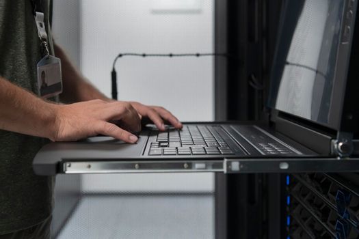 Close up on Data Center Engineer hands Using keyboard on a supercomputer. Server Room Specialist Facility with Male System Administrator Working with Data Protection Network for Cyber Security.