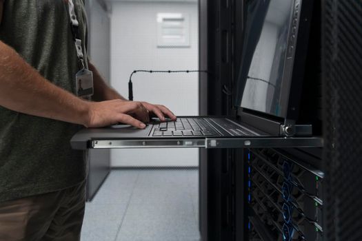 Close up on Data Center Engineer hands Using keyboard on a supercomputer. Server Room Specialist Facility with Male System Administrator Working with Data Protection Network for Cyber Security.