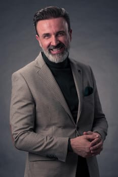 Portrait of a stylish elegant senior businessman with a beard and casual business clothes in photo studio isolated on dark background gesturing with hands. High quality photo