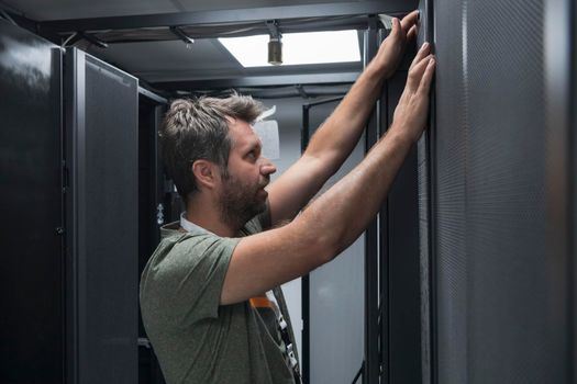 IT engineer working In the server room or data center. The technician puts in a rack a new server of corporate business mainframe supercomputer or cryptocurrency mining farm.