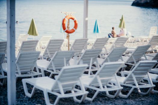 Several white sun loungers and an umbrella on a deserted beach. The perfect vacation concept