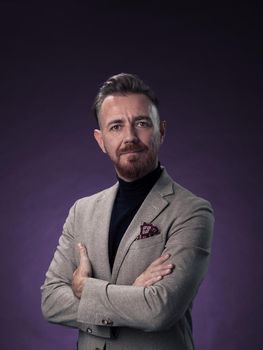 Portrait of a stylish elegant senior businessman with a beard and casual business clothes in photo studio isolated on dark background gesturing with hands. High quality photo