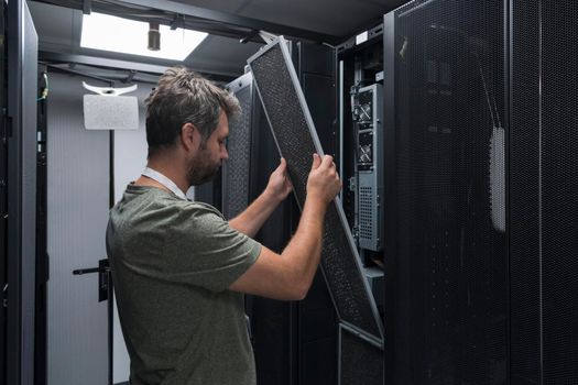 IT engineer working In the server room or data center. The technician puts in a rack a new server of corporate business mainframe supercomputer or cryptocurrency mining farm.