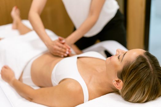 Middle-aged woman having a belly massage in a beauty salon. Body care treatment in a beauty centre.