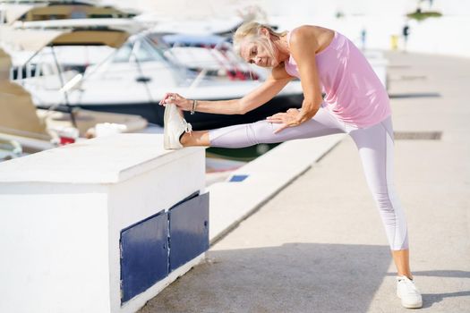 Mature sportswoman stretching her legs after exercise. Concept of healthy living in the elderly. Senior woman in fitness clothing. Older female doing sport to keep fit.