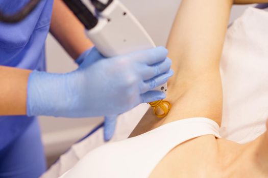 Woman receiving underarm laser hair removal at a beauty center. Laser depilation treatment in an aesthetic clinic.