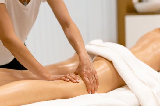 Woman receiving a leg massage with massage candle oil. Body care treatment in a beauty centre.