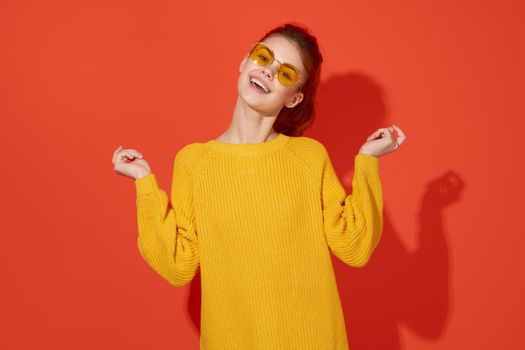 cheerful woman in yellow glasses holding her head fashion red background. High quality photo