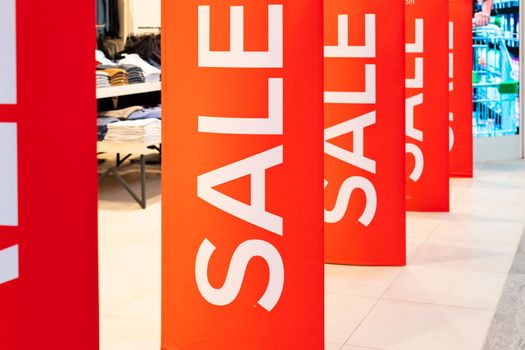 Sale sign at the entrance to clothing store - large red panels with white words.