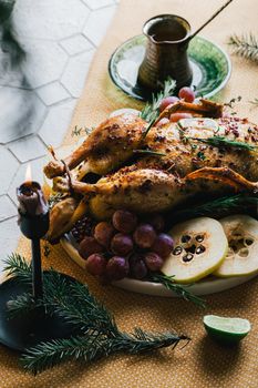 A duck baked for Thanksgiving as a symbol of family unification at a common holiday table. Still life in orange tones, shot in a light key on a white ceramic background. The atmosphere of the festival and celebration. The dish is decorated with grapes, lime, quince and aromatic herbs.