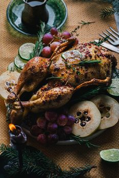 A duck baked for Thanksgiving as a symbol of family unification at a common holiday table. Still life in orange tones, shot in a light key on a white ceramic background. The atmosphere of the festival and celebration. The dish is decorated with grapes, lime, quince and aromatic herbs.