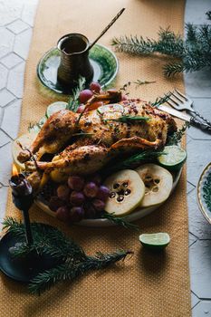 A duck baked for Thanksgiving as a symbol of family unification at a common holiday table. Still life in orange tones, shot in a light key on a white ceramic background. The atmosphere of the festival and celebration. The dish is decorated with grapes, lime, quince and aromatic herbs.