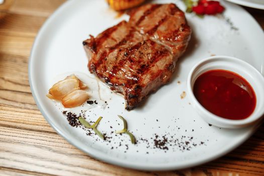 BBQ Grilled rib eye steak, fried rib-eye beef meat on a plate with green salad. Dark background.