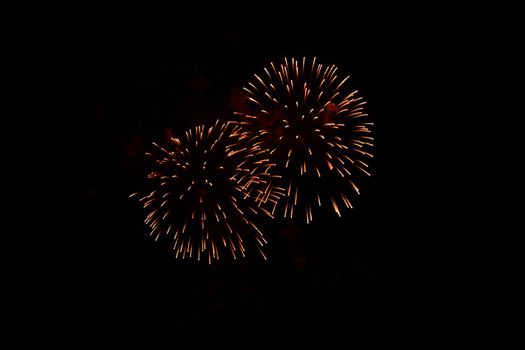 Blurred multicolored fireworks lights against the dark night sky. Festive fireworks. Light defocus