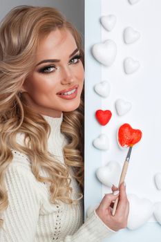 Beautiful young woman painting hearts with red paint Valentine day love concept