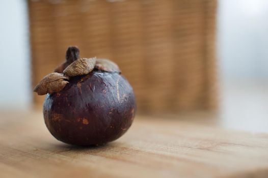 Mangosteen fruit with dark purple skin on wooden table, the queen of exotic fruits. Healthy eating concept.