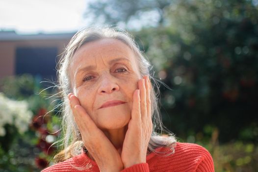 Portrait of a mature woman with grey hair spending time outdoors during sunny day, happy retirement.