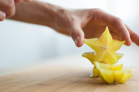 Female hands are holding slice of exotic ripe starfruit or averrhoa carambola. Healthy food, fresh organic star apple fruit.