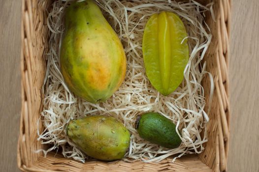 Big basket of fresh tropical fruits, carambola, papaya, feijoa, prickly pear or opuntia. Exotic fruits, healthy eating concept, top view