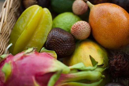 Big basket of fresh tropical fruits, passion fruit, carambola, dragon fruit or pitaya, mangosteen, lichi, granadilla. Exotic fruits, healthy eating concept.