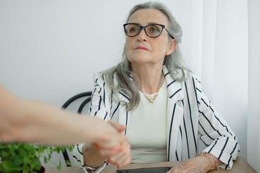 Mature businesswoman is leading an interview with new colleague and shaking their hand at the end. Business people concept.