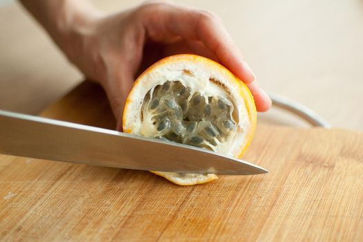 Fresh organic ripe granadilla or yellow passion fruit cut in half on a wooden board. Exotic fruits, healthy eating concept.