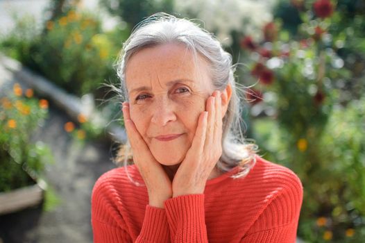 Portrait of a mature woman with grey hair spending time outdoors during sunny day, happy retirement.