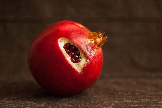 Juicy garnet ripe pomegranate fruit on wooden background. Healthy eating, exotic fruits