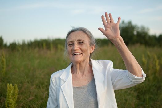 Portrait of senior woman with grey hair and face with wrinkles wearing white jacket and relaxing at park during sunny day, happy retirement, mothers day concepts