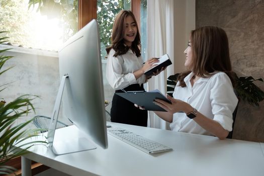 Two asian business partnership coworkers discussing a financial planning graph and company during a budget meeting in office room