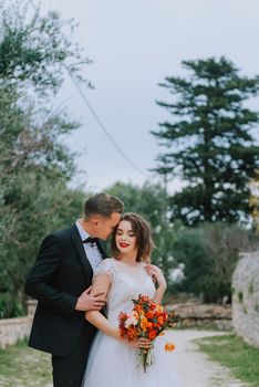 Happy stylish smiling couple walking in Tuscany, Italy on their wedding day. The bride and groom walk down the street by the hands. A stylish young couple walks. Husband and wife communicate nicely. Lovers run through the streets of the city.