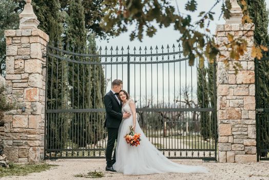 Happy stylish smiling couple walking in Tuscany, Italy on their wedding day. The bride and groom walk down the street by the hands. A stylish young couple walks. Husband and wife communicate nicely. Lovers run through the streets of the city.