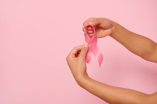 Woman's hands holding a pink ribbon, symbol of World Breast Cancer awareness Day, in 1 st October. Woman's health and medical concept, October Pink day, World Cancer Day, national Cancer Survivor Day.