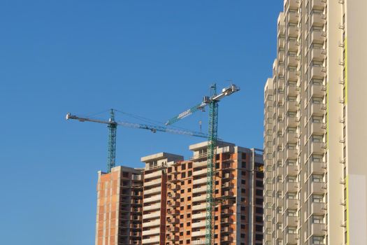 Tower cranes construction site building company property investment building real estate apartments construction build. New building construction background clear blue sky. Multistory house. Mortgage