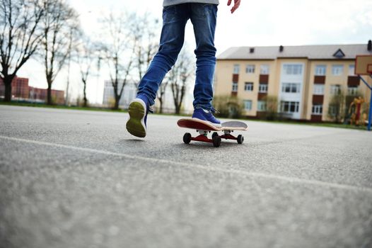 View from the back of skateboarder legs. Kid riding skateboard outdoor. Concept of leisure activity, sport, extreme, hobby and motion.