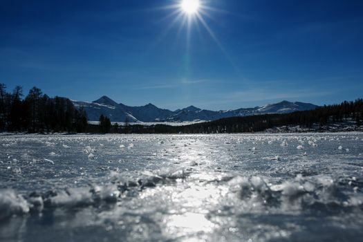 Panorama of frozen lakes, covered with ice and snow. In clear weather with a blue sky in the sunlight. Altai, Ulagan Pass.